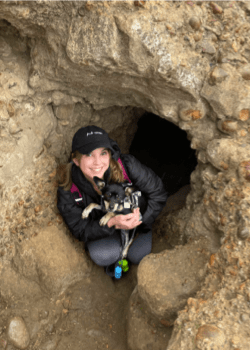 Image of a woman holding a puppy near a cave hole