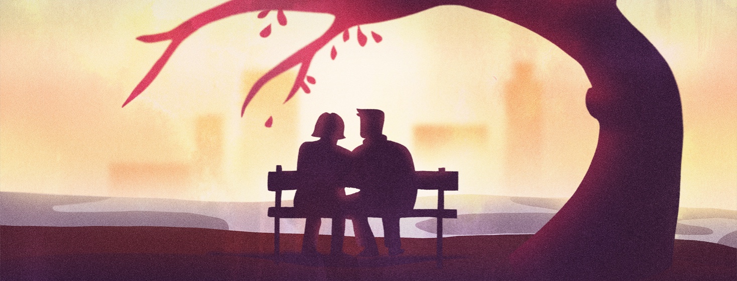 A couple sitting on a park bench at sunset